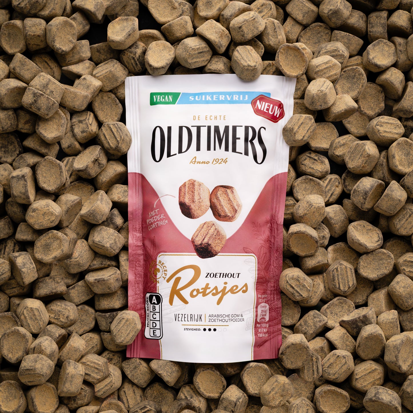 Oldtimers Zoethout Rotsjes suikervrije vegan snoepjes in een staande verpakking, omringd door zoethoutblokjes op een houten ondergrond.